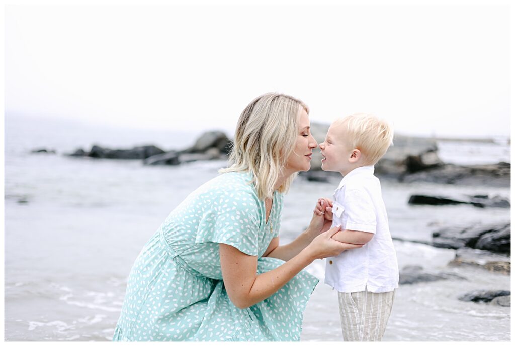 Mother and son standing nose to nose by the waves at the beach during NH Family Beach Photo Session.