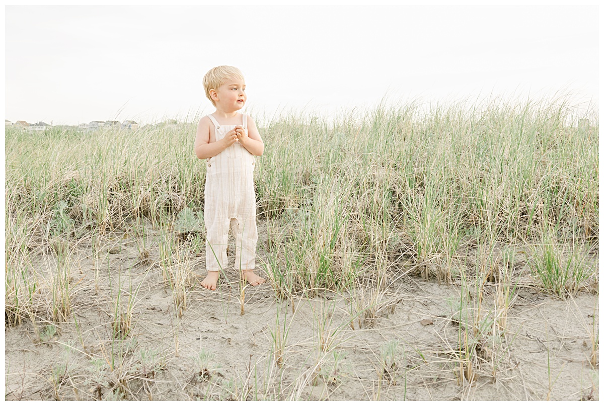 Young boy wearing soft tones soaking in the sunshine during a golden hour session with Kathleen Jablonski Photography at Hampton Beach in NH. 